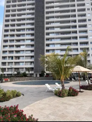 a large apartment building with two chairs and a palm tree at Apartamento frente al mar- edificio santa marina in Santa Marta