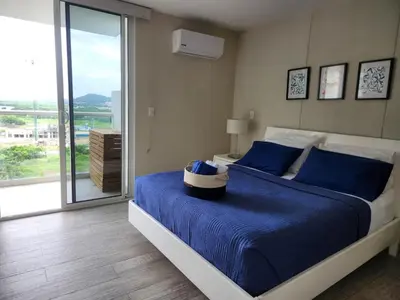 a bedroom with a bed with blue sheets and a window at Tu refugio en la playa, moderno cómodo con estilo in Cartagena de Indias