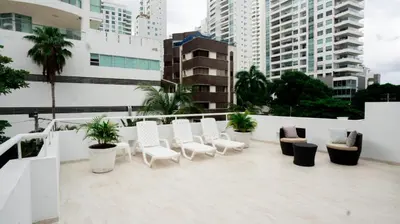 a balcony with white chairs and plants and buildings at MQ CROWN HOUSE CASTIllO in Cartagena de Indias