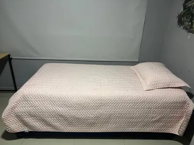 a small bed in a room with a white wall at Gisela Wax More Hostel in Cartagena de Indias