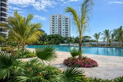 a pool with palm trees and a tall building at Apto nuevo Frente al Mar con Piscina Wifi cerca aeropuerto in Santa Marta