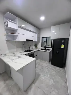 a kitchen with white cabinets and a black refrigerator at Villa Sabanilla Casa bifamiliar campestre con piscina privada Aire acondicionado Tranquilidad total in Puerto Colombia