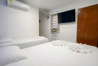 a room with two beds and a flat screen tv at Hotel Getsemaní Central in Cartagena de Indias