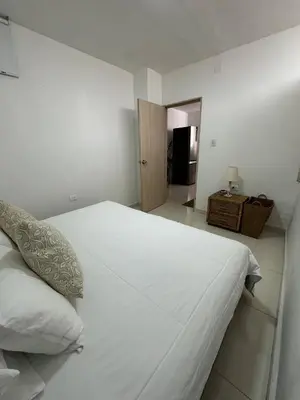 a white bed in a white bedroom with a door at Comfortable in the heart of the city! in Estación El Salto
