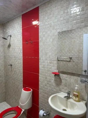 a bathroom with a toilet and a sink and red wall at Rojas House in Barranquilla