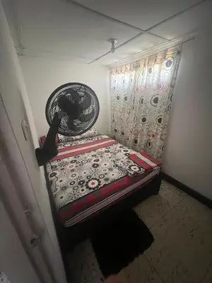 a small room with a bed with a fan at Carnival Hostel BAQ in Barranquilla