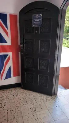 a black door with a british flag behind it at Carnival Hostel BAQ in Barranquilla