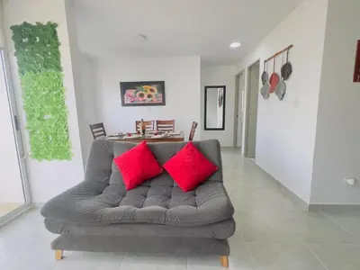a living room with a couch with two red pillows at Beach Lotus 1203 in Cartagena de Indias