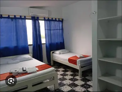 a bedroom with two beds and a window with blue curtains at Hotel Palma Azul in Coveñitas