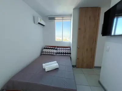 a room with a bed and a window and a door at Acogedor Apto Cerca A La Playa WiFi Piscina AC in Cartagena de Indias