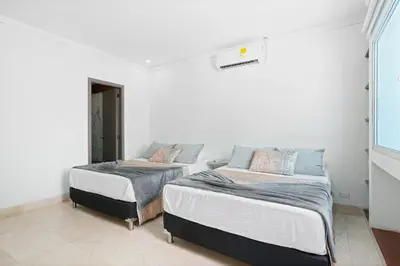 two beds in a room with white walls at 10BR Mansion Beachfront w Pool and Disco in Cartagena de Indias