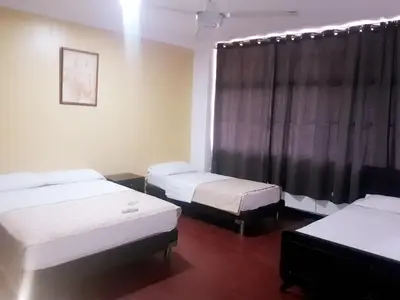 a room with three beds and a window at hotel hispanoamericano in Barranquilla