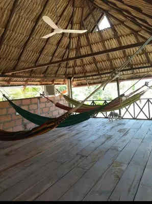 a hammock in a straw straw hut with a wooden floor at Cabaña y Hospedaje Las Gaviotas in Moñitos
