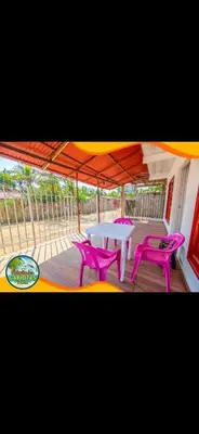 a patio with a table and two pink chairs at Cabaña y Hospedaje Las Gaviotas in Moñitos