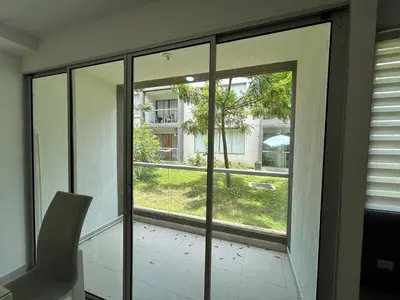 a glass door with a chair in a room with a window at Serena Del Mar Apartment in Cartagena de Indias