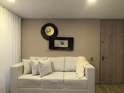 a white couch in a living room with a clock at Luxury apartment in Barranquilla