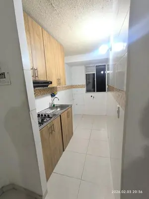 a kitchen with wooden cabinets and a white tile floor at Apartamento acogedor y fresco cerca al norte de barranquilla in Barranquilla