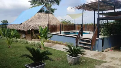 a resort with a swimming pool with a hammock and a hut at Casaroca in Turbaco