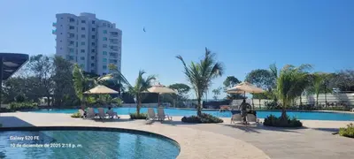 a swimming pool with chairs and umbrellas and a building at Apartamento vacacional con acceso al mar in Santa Marta