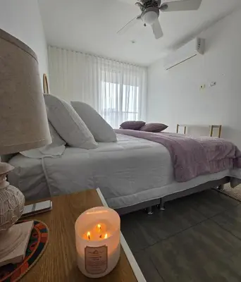 a bedroom with a bed with a candle on a table at Luxury Oceanfront Apartment Spiaggia 2BR 3BA Playa azul Cartagena in Cartagena de Indias