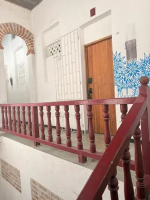 a staircase with a red rail and a wooden door at Cozy apartment Old City in Cartagena de Indias
