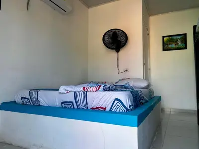 a room with a bed with a fan on the wall at Costa Azul Isla Fuerte in Isla Fuerte