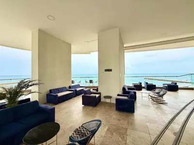 a lobby with blue couches and chairs in a building at 2Br apartment in front of the beach in Cartagena de Indias