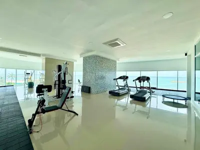 a gym with cardio equipment in a large room with windows at 2Br apartment in front of the beach in Cartagena de Indias