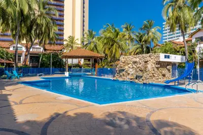 a swimming pool in a resort with palm trees at Casa en conjunto cerrado, frente al mar in Santa Marta