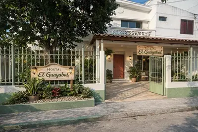 a house with a sign in front of a gate at Casa Guayabal hostal& cocina in Cartagena de Indias