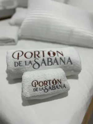 three towels on a bed with the words porton de las palmas at Hotel Portón de La Sabana in San Onofre
