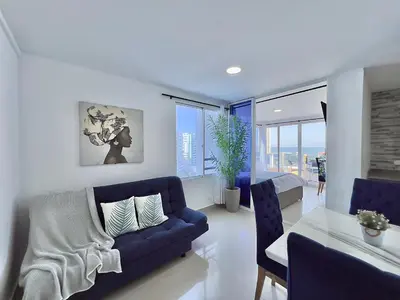 a living room with a blue couch and a table at Apartamento con vista al mar - Riviera Mulata Beach in Cartagena de Indias