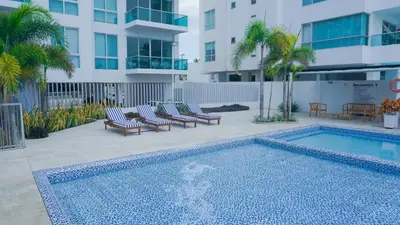a swimming pool with lounge chairs next to a building at Magico Apartamento Frente al Mar 3 Habitaciones BM81 in Coveñas
