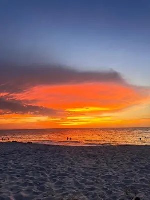 a sunset on a beach with people in the water at New apartment on the 18th floor in Santa Marta with ocean views in Simón Bolivar