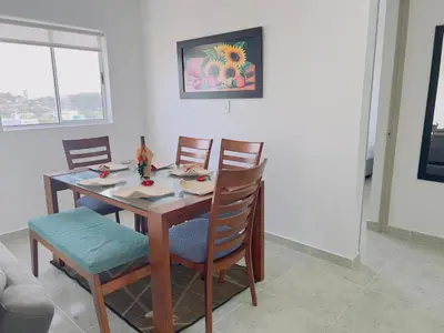 a dining room table with four chairs and a painting on the wall at Beach 1203 Lotus Cartagena in Cartagena de Indias