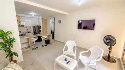 a living room with white chairs and a fan at Apartamento moderno cerca del mar - Cartagena in Cartagena de Indias