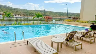 a swimming pool with two chairs and a person sitting next to it at Apartamento moderno cerca del mar - Cartagena in Cartagena de Indias