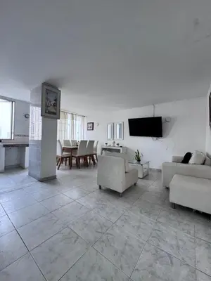 a white living room with couches and a tv at Delfines De Bocagrande in Cartagena de Indias