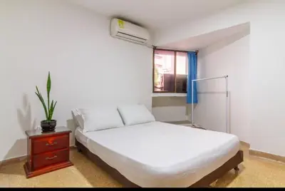 a white bedroom with a bed and a window at Refugio Cartagena Kawica Bocagrande in Cartagena de Indias
