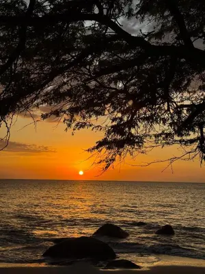a sunset over the ocean with rocks in the foreground at Santa Marina Caribbean Dreams in Santa Marta