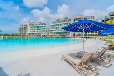 a beach with chairs and an umbrella and a swimming pool at kristal lagoon view apartement in Cartagena de Indias