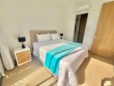 a bedroom with a bed with a blue blanket on it at kristal lagoon view apartement in Cartagena de Indias