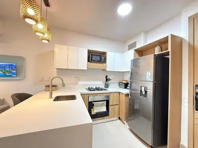 a kitchen with white cabinets and a stainless steel refrigerator at Suite Exclusiva Baia Kristal, Zona Kabo 3 in Cartagena de Indias