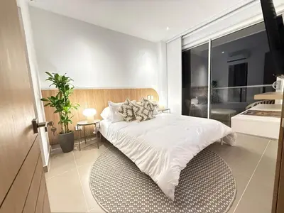 a bedroom with a white bed with a large window at Suite Exclusiva Baia Kristal, Zona Kabo 3 in Cartagena de Indias