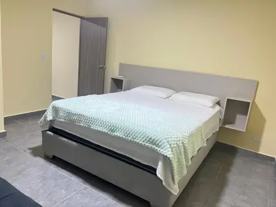 a bedroom with a large bed with a green blanket at Nora la bella in Barranquilla