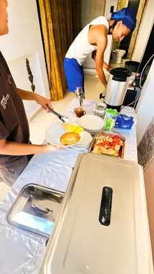 two people standing at a table with food on it at Habitaciones CALA Capsulas en Ciudad Jardín, desayuno incluido in Barranquilla