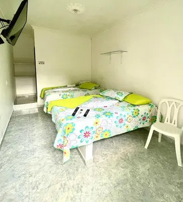 a bedroom with two beds and a chair at Hotel Y Restaurante La Quinta in Cartagena de Indias