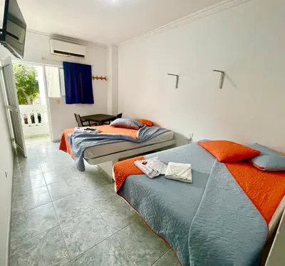 a bedroom with two beds and a tv on the wall at Hotel Y Restaurante La Quinta in Cartagena de Indias
