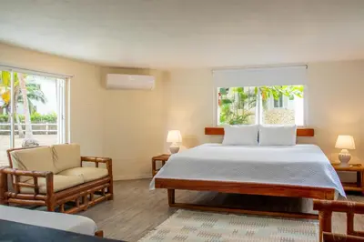 a bedroom with a bed and a chair and windows at Quinta del Mar El Paraiso in Tolú