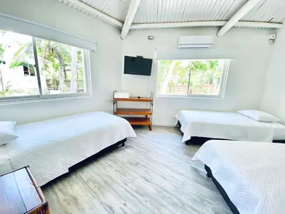 two beds in a room with two windows at Quinta del Mar El Paraiso in Tolú
